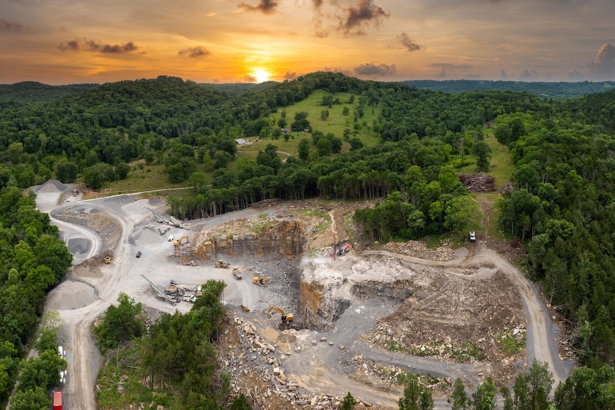 Wide-Angle Shot Of A Limestone Quarry Operation With Heavy Trucks And Excavation Equipment In Action; Mining Truck Muffler Systems Help Reduce Noise And Emissions.