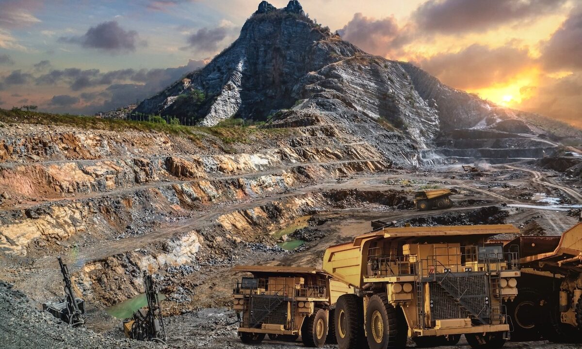 Mining Trucks Operating In A Mountainous Open-Pit Mine At Sunset, Equipped With Heavy-Duty Parts For Extreme Terrain