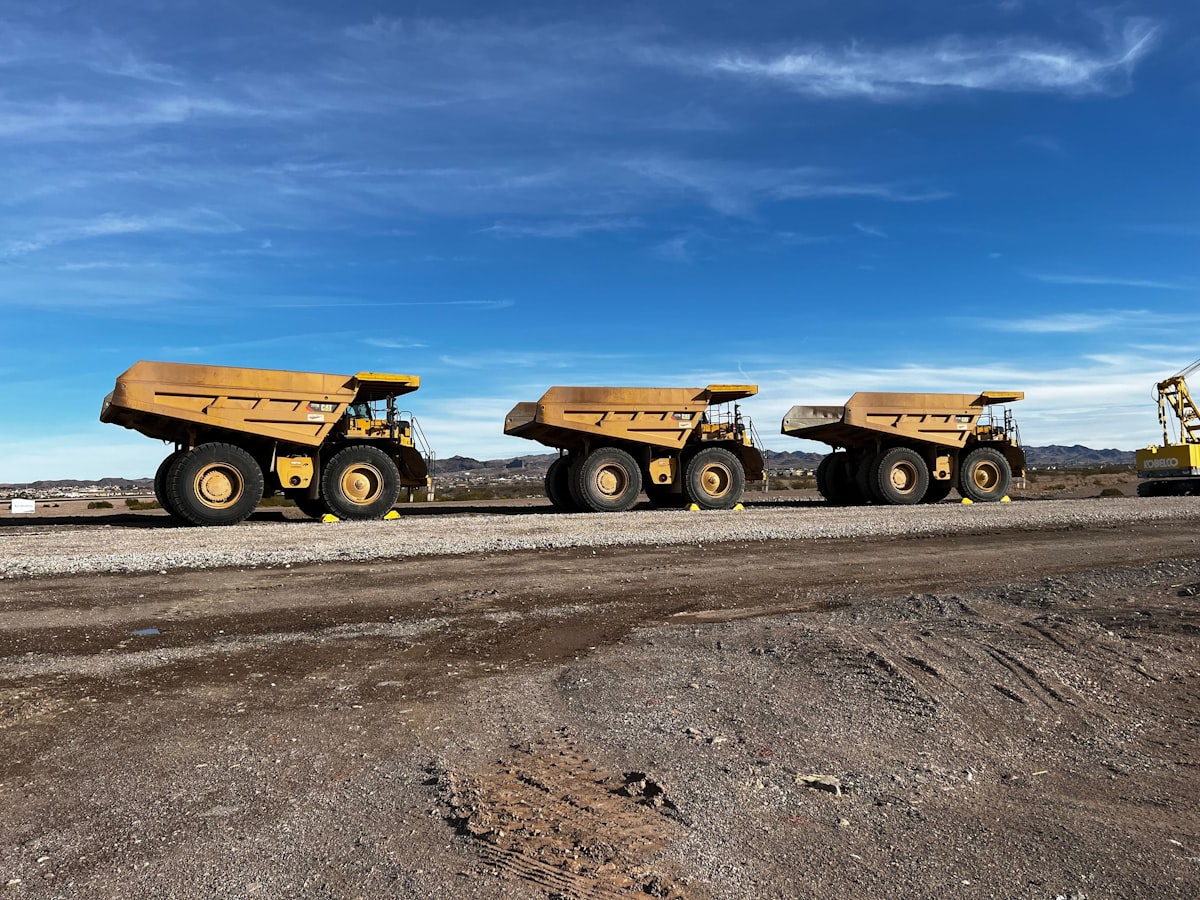 Fleet Of Yellow Haul Trucks On Mine Road — Mining Truck Overheating Warning Signs For Operators